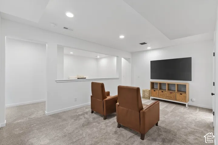 Finished lower-level space featuring recessed lighting, a neutral gray carpet, white walls, and an open wall architectural detail