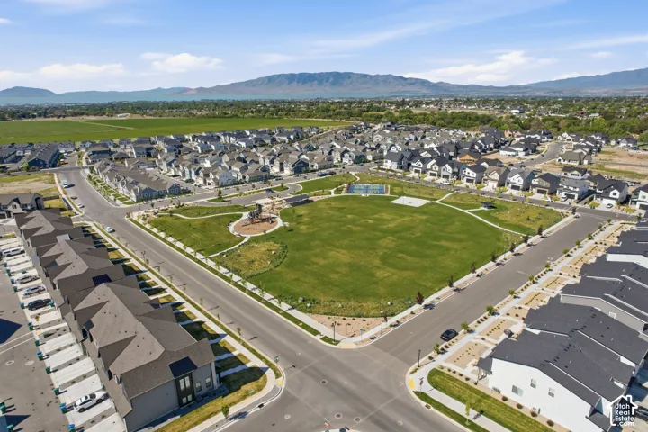Expansive green space featuring a playground, surrounded by a residential neighborhood with new construction homes and mature landscaping