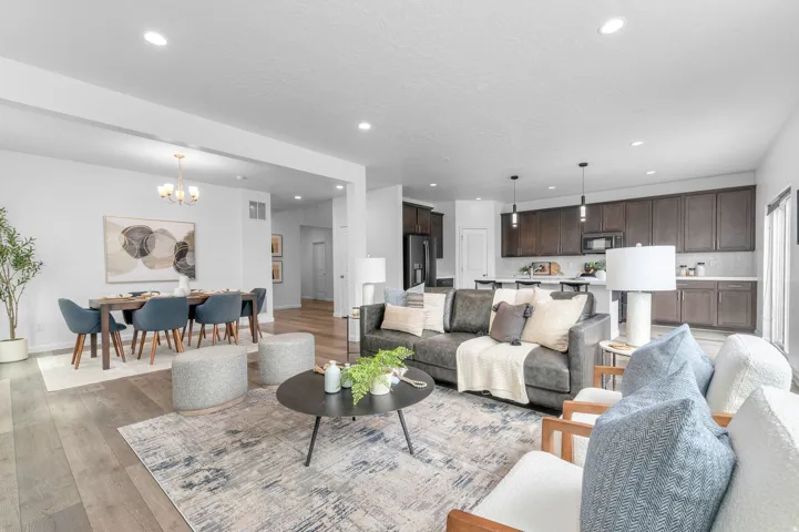 Open-concept living space featuring wood-finish flooring, recessed lighting, and a dining area with a chandelier