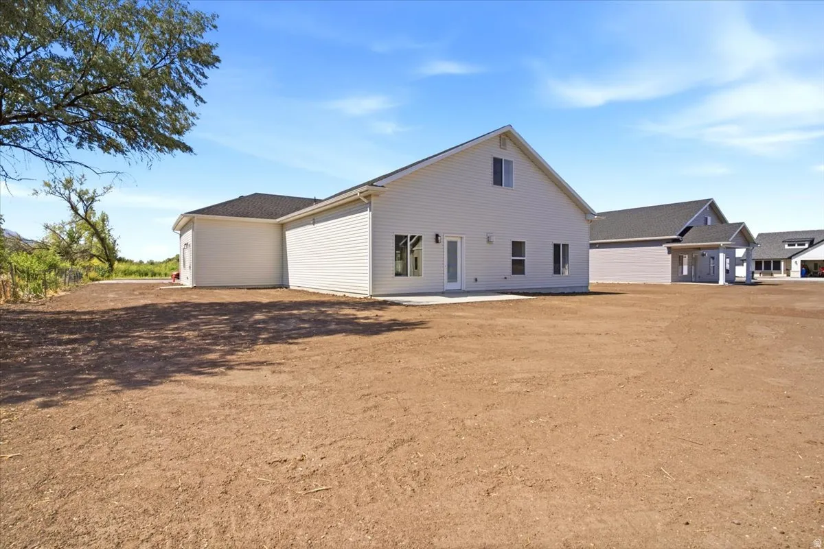 Expansive, undeveloped lot featuring a newly constructed residence with white siding and dark roofing