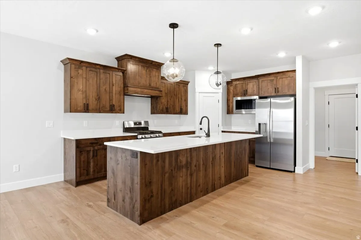 Spacious kitchen featuring an island with a matte black faucet, dark wood-finish cabinetry, stainless steel appliances, white countertops
