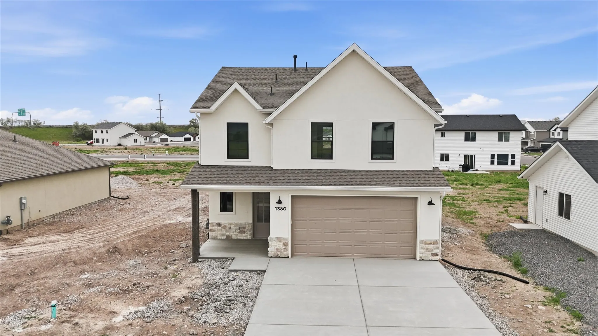 Contemporary white stucco exterior with stone accents, a two-car garage, and a covered entry