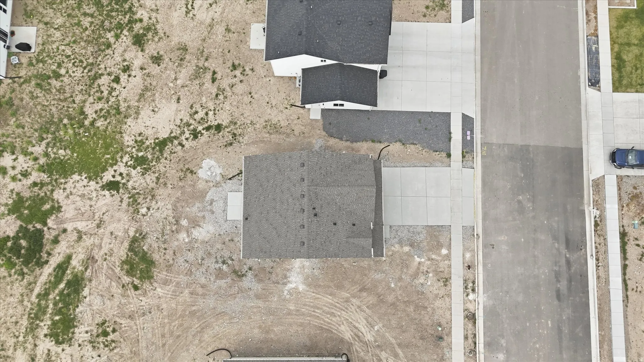 Aerial perspective of a property featuring a dark shingled roof and a concrete driveway