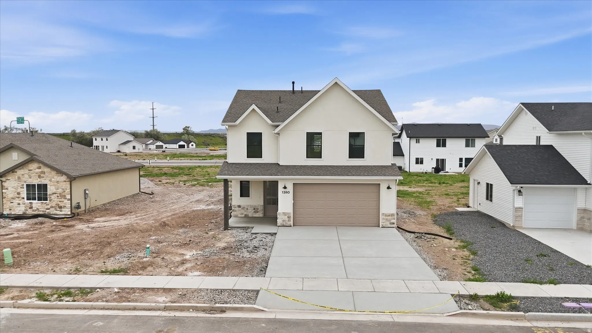Modern two-story home featuring a light-toned exterior, dark trim windows, and a prominent front-facing garage