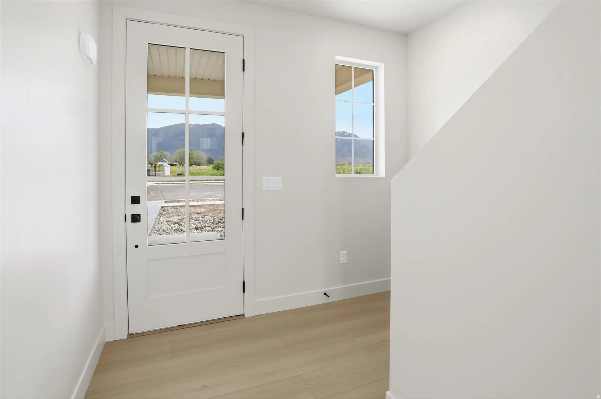 Entryway featuring a white paneled door with multiple glass lites, light wood-finish flooring, and a large side window