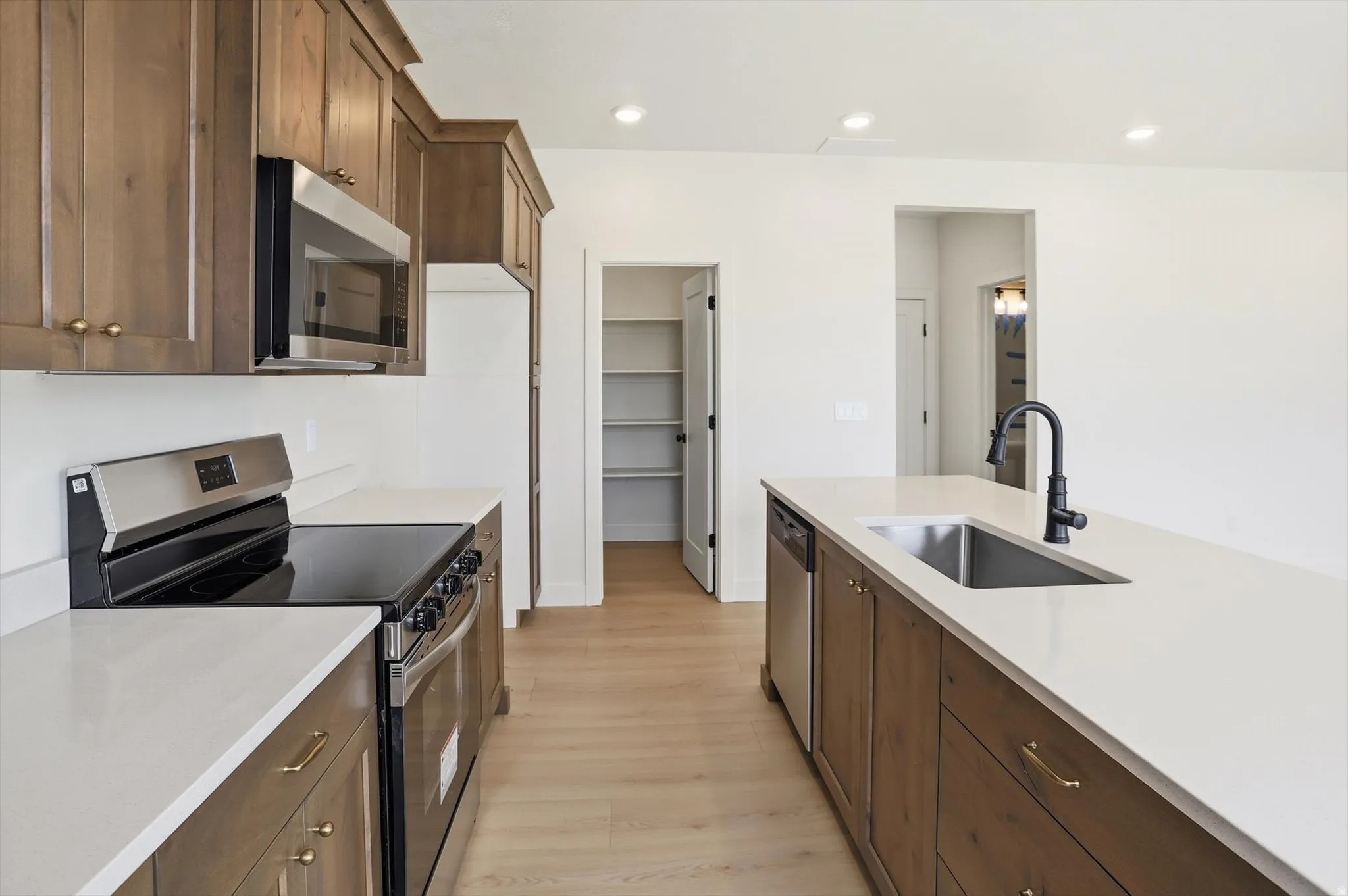 Modern kitchen featuring wood-finish cabinetry, light-toned countertops, and stainless steel appliances