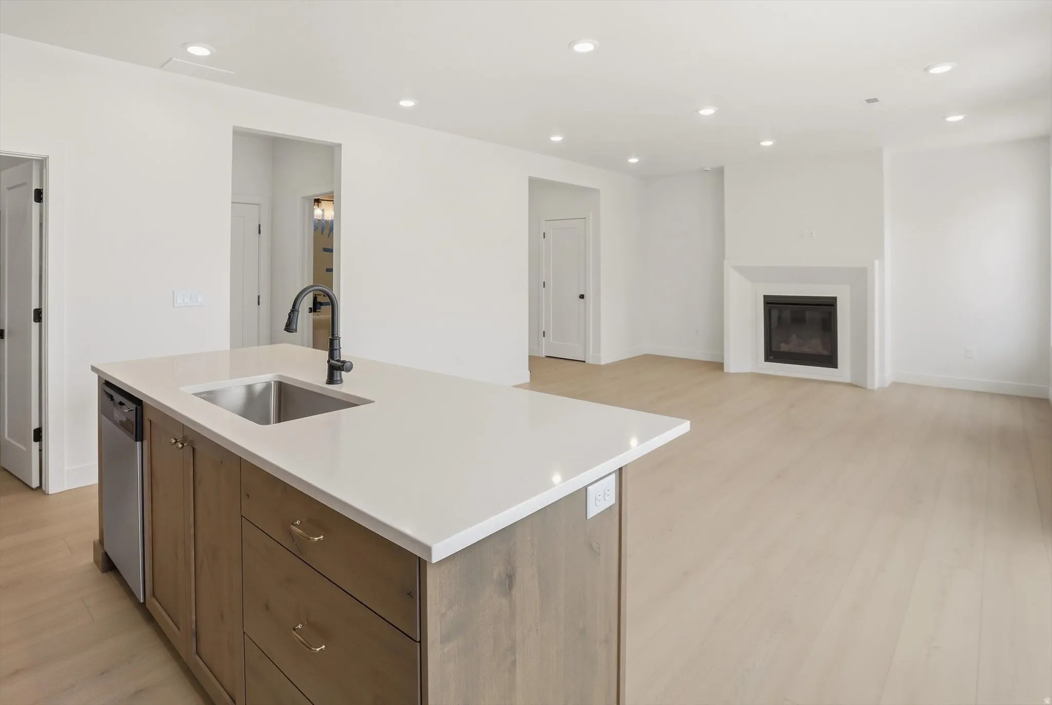 Central kitchen island with a stainless steel sink, matte black faucet, and light-toned countertop