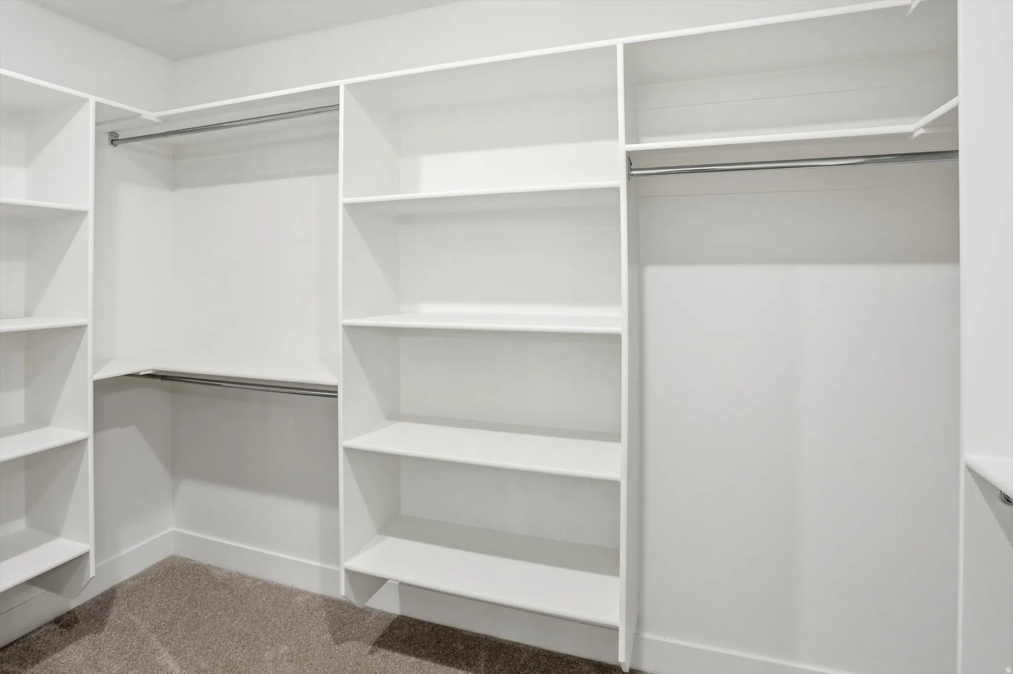 Custom closet system featuring white shelving and chrome hanging rods