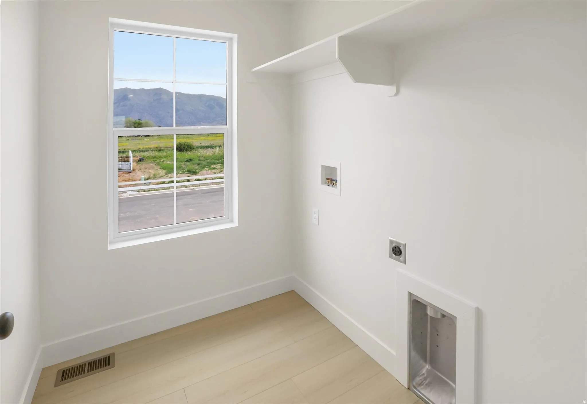 Utility space featuring light wood-finish flooring and a white window frame