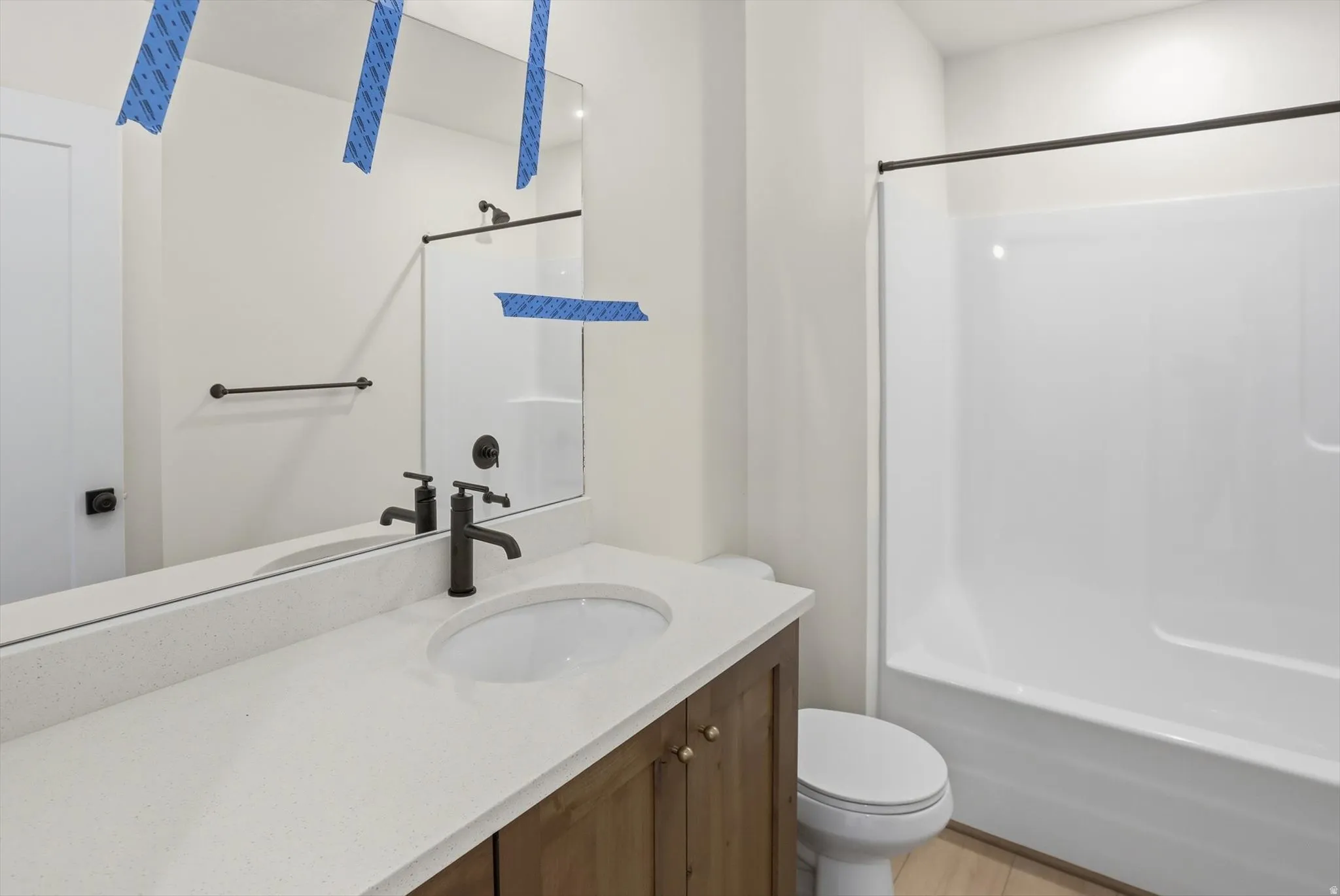 Bathroom with a wood-finish vanity, integrated white sink, and white countertop