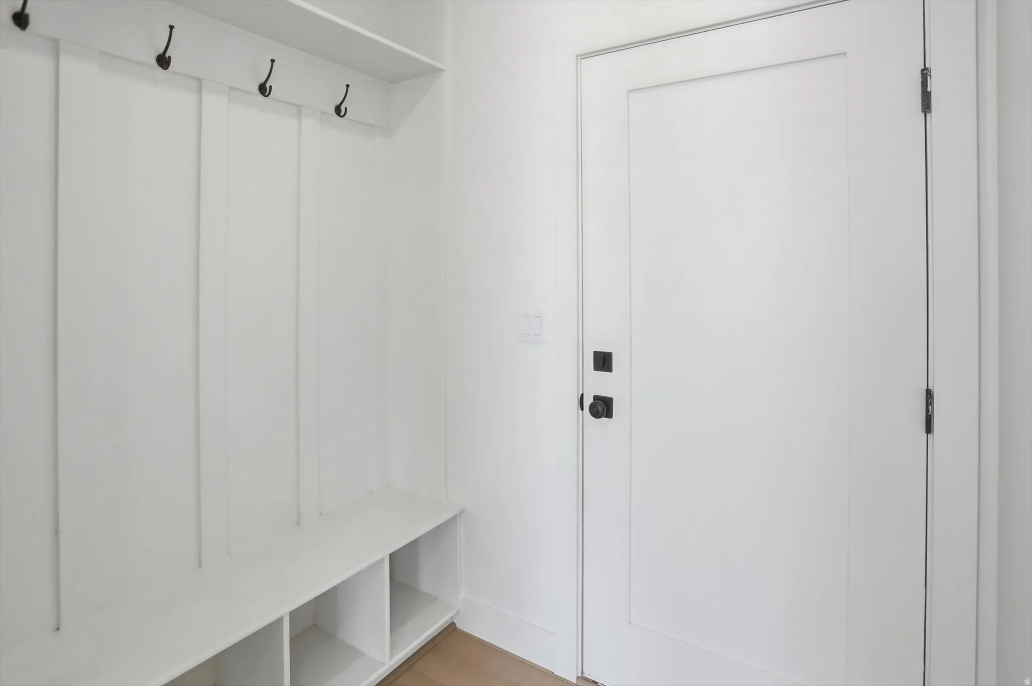 Built-in mudroom bench with cubby storage and black coat hooks