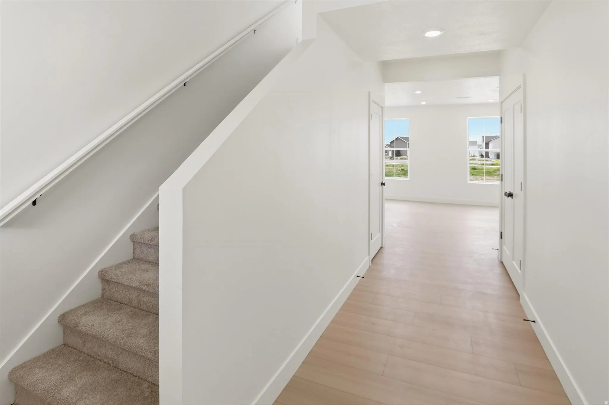 Entryway featuring wood-finish flooring and a carpeted staircase with a white handrail