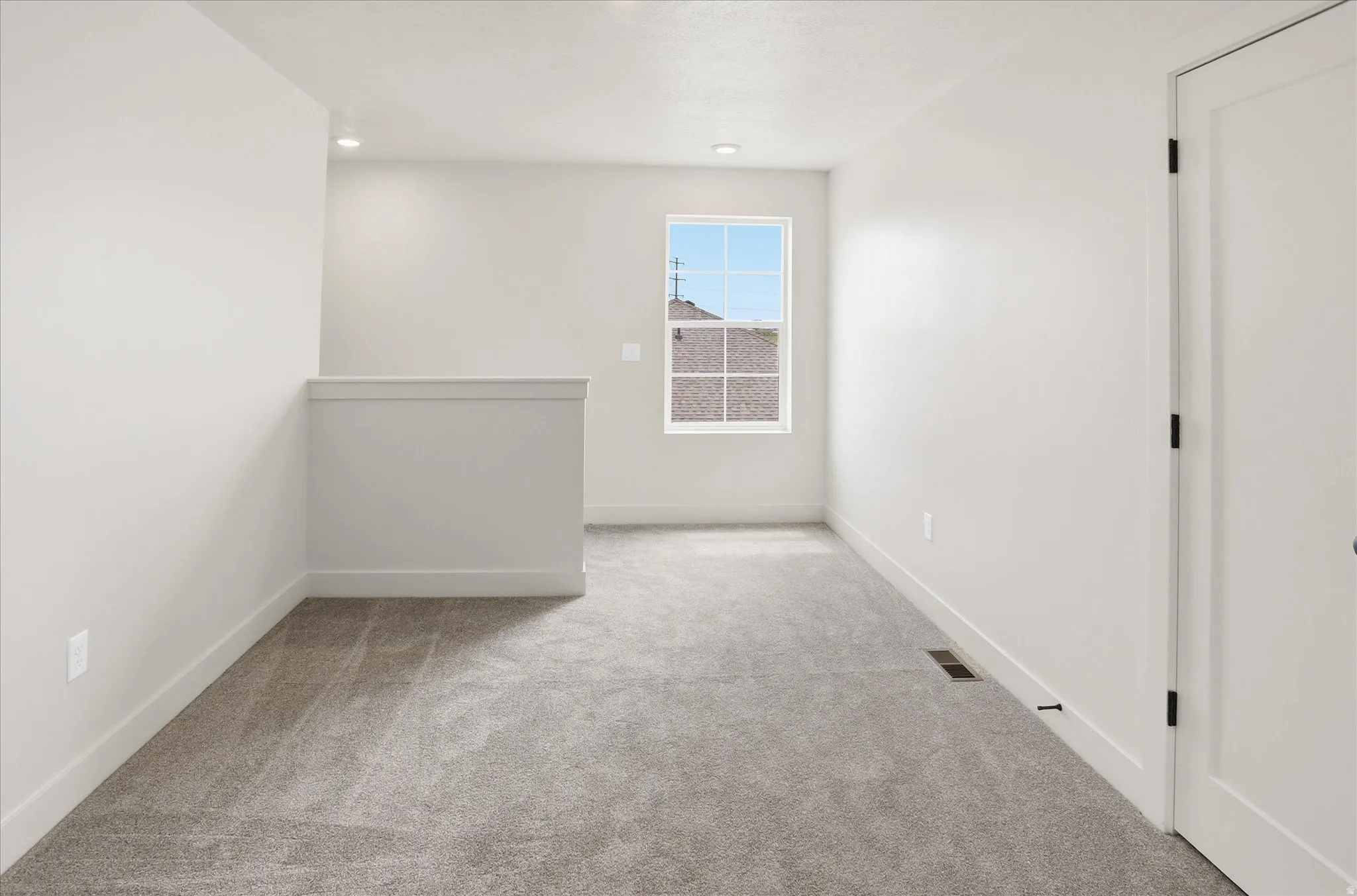 Open concept room featuring neutral carpeting, white walls, and a large window providing natural light