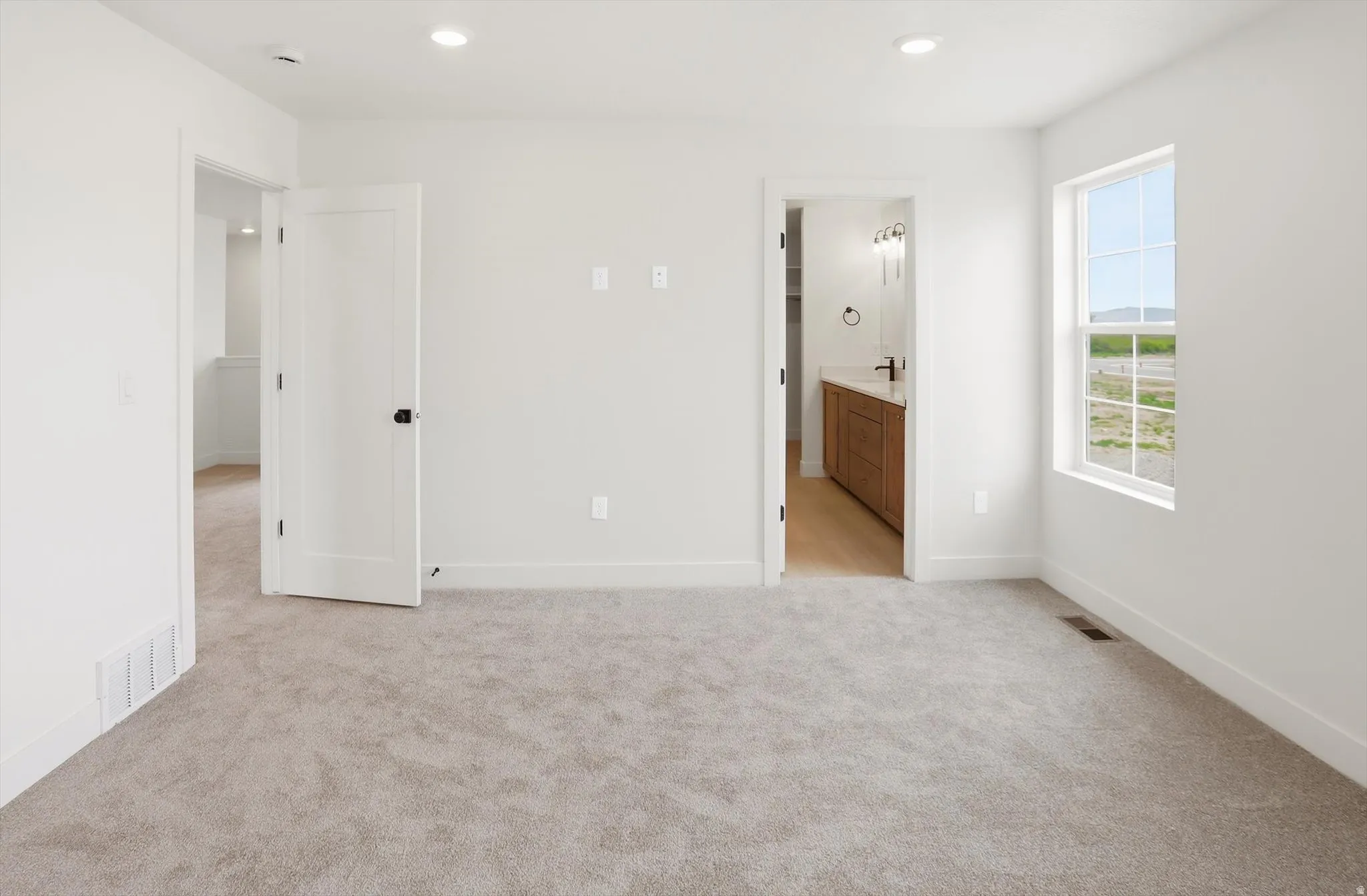 Spacious room featuring neutral carpeting, recessed lighting, and a white-framed window
