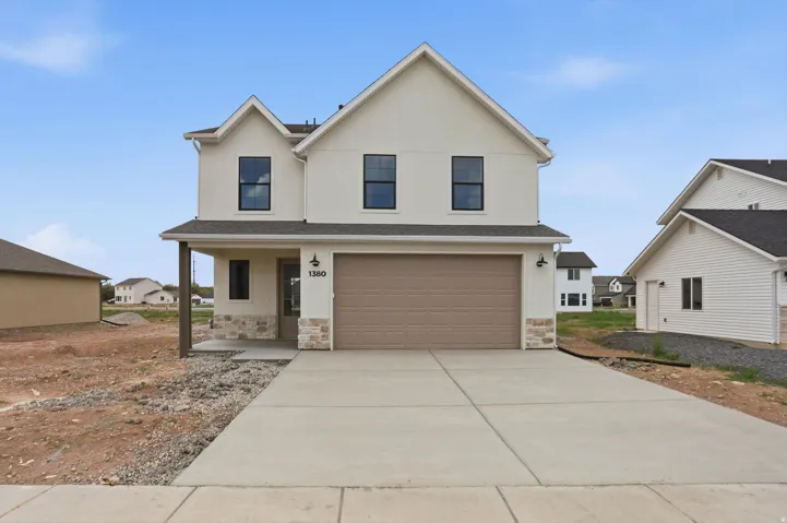 Two-story residence featuring a stucco exterior with stone accents, a two-car garage, and a covered entry