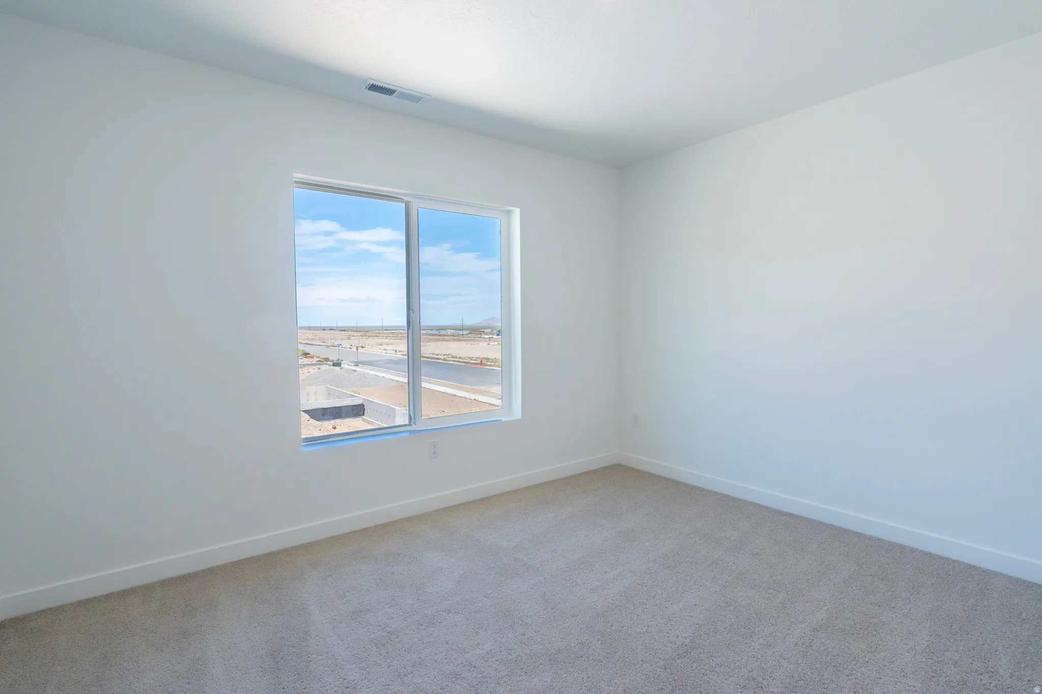 Light-toned carpeting, white painted walls, and a large window with a distant landscape