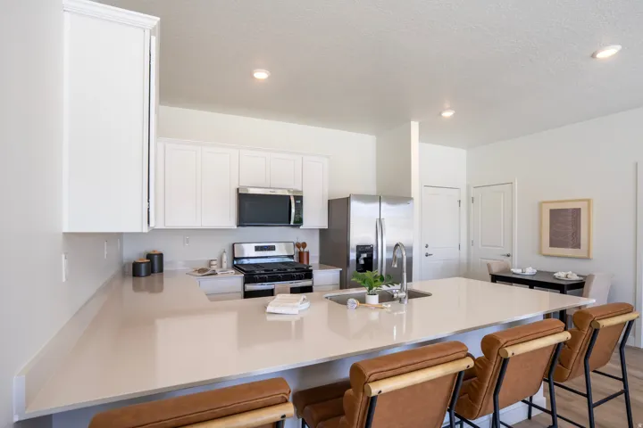 Kitchen featuring white cabinetry, stainless steel appliances, a center island with an undermount sink, and recessed lighting
