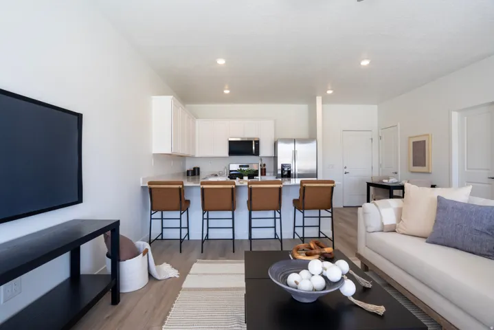 Open-concept living space featuring wood-finish flooring, white cabinetry, stainless steel appliances, and recessed lighting