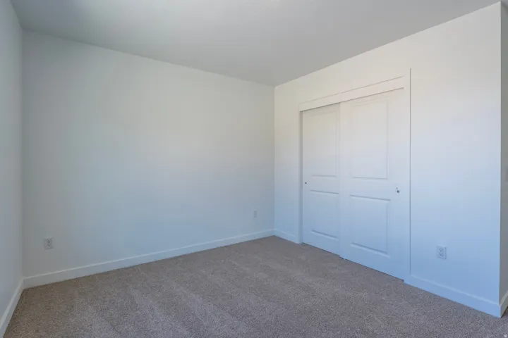 Wall-to-wall carpeting and white walls with a built-in closet featuring bi-fold panel doors