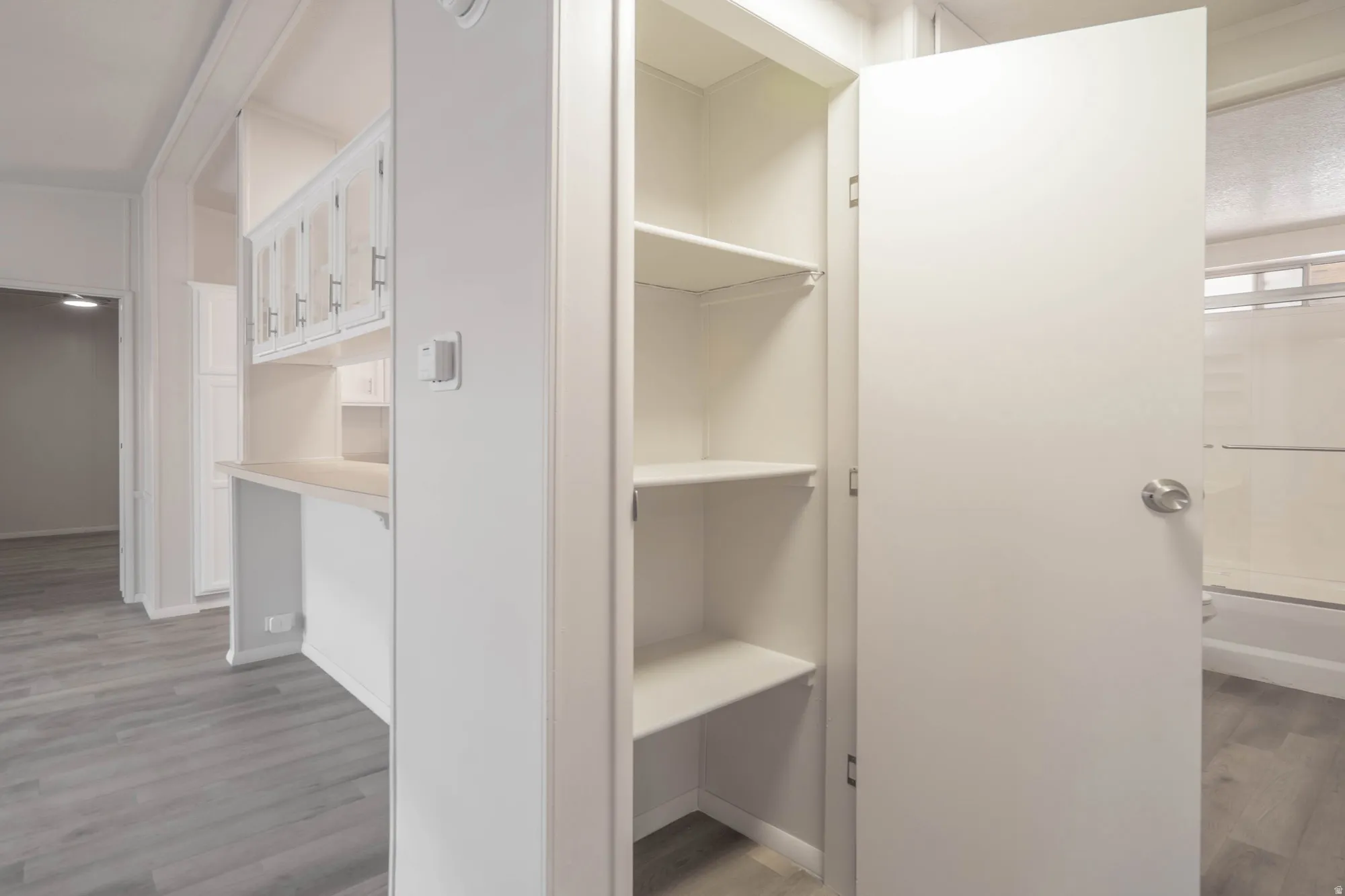 Built-in storage solutions featuring adjustable shelving, a dedicated desk area, and upper cabinetry with glass inserts