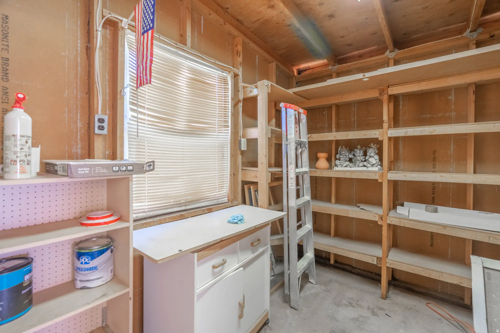 Storage area featuring exposed wood framing and extensive built-in shelving