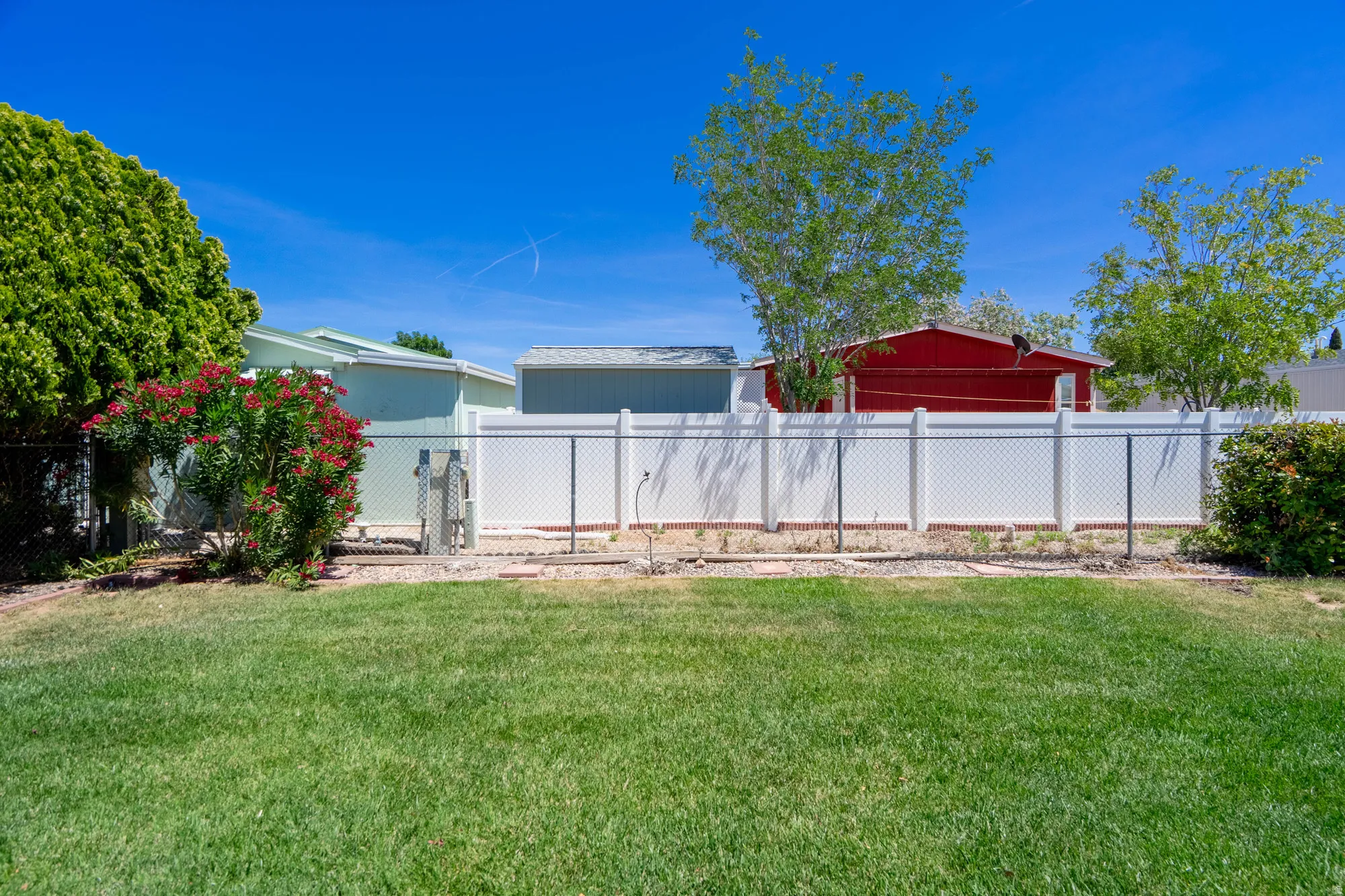 Expansive grassy yard area featuring a chain link fence with a privacy screen