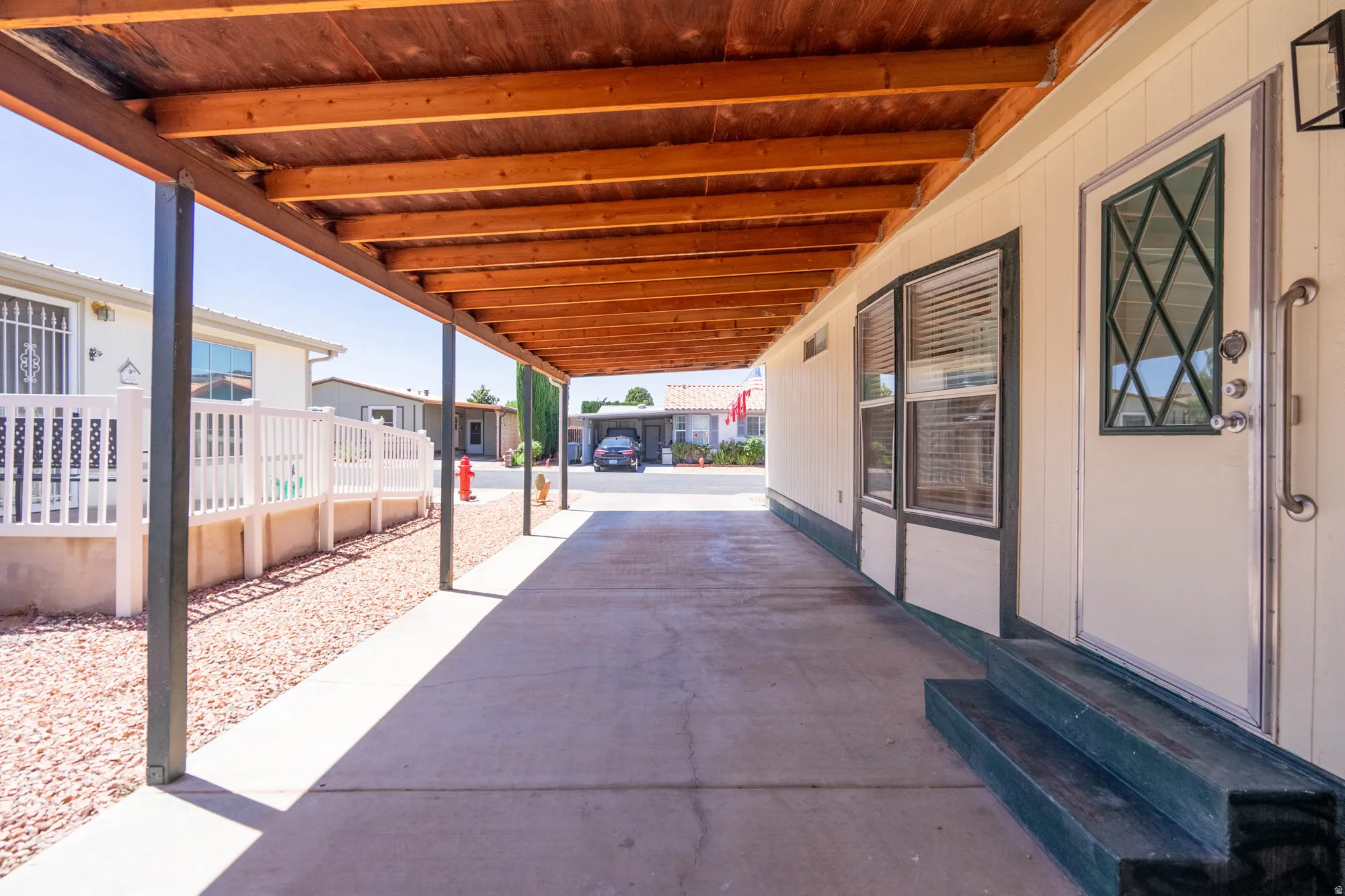 Covered carport featuring a wood-finish ceiling, concrete flooring, and metal support posts