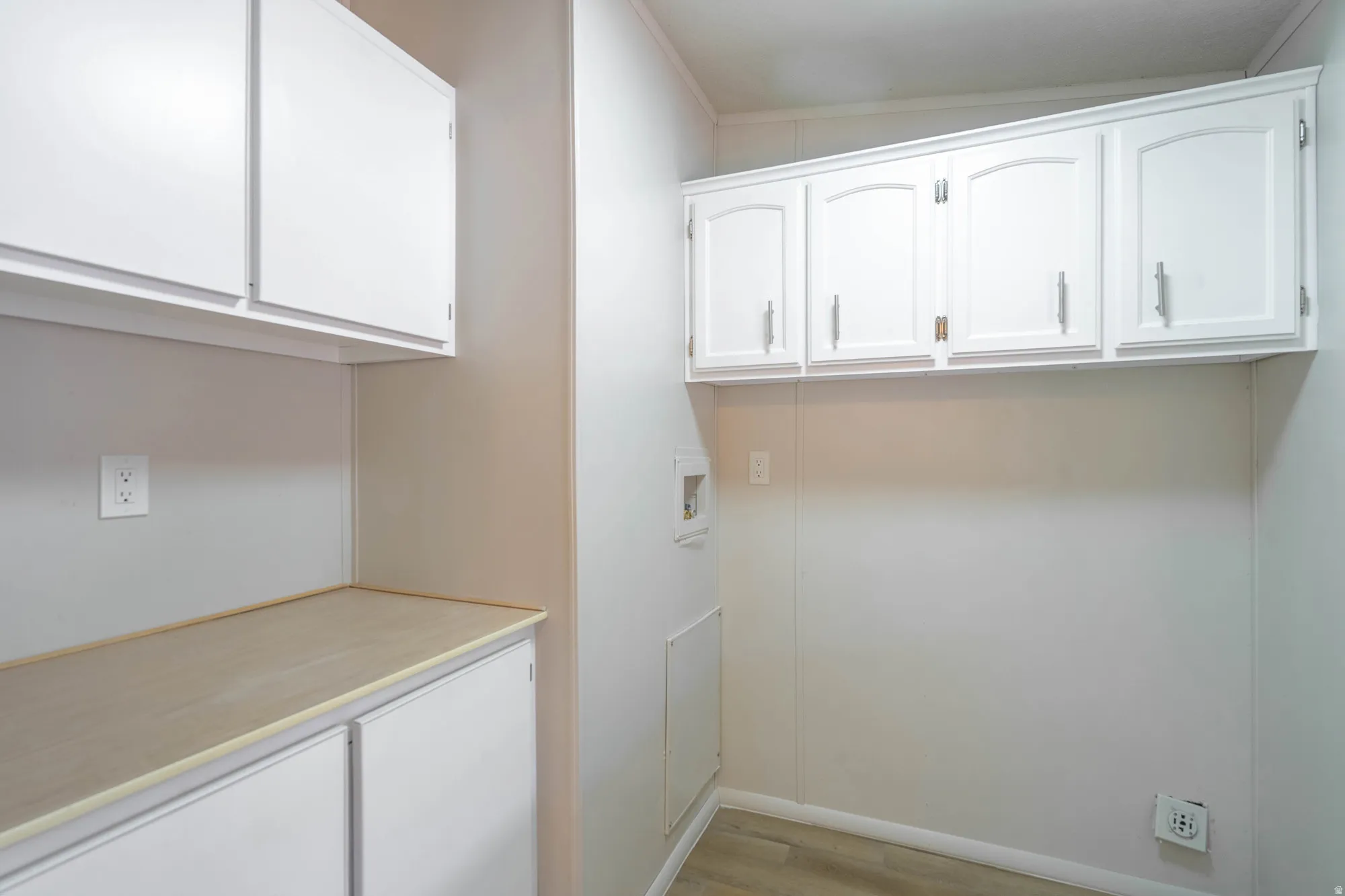 Utility area featuring white cabinetry, a light wood-finish countertop, and vinyl plank flooring
