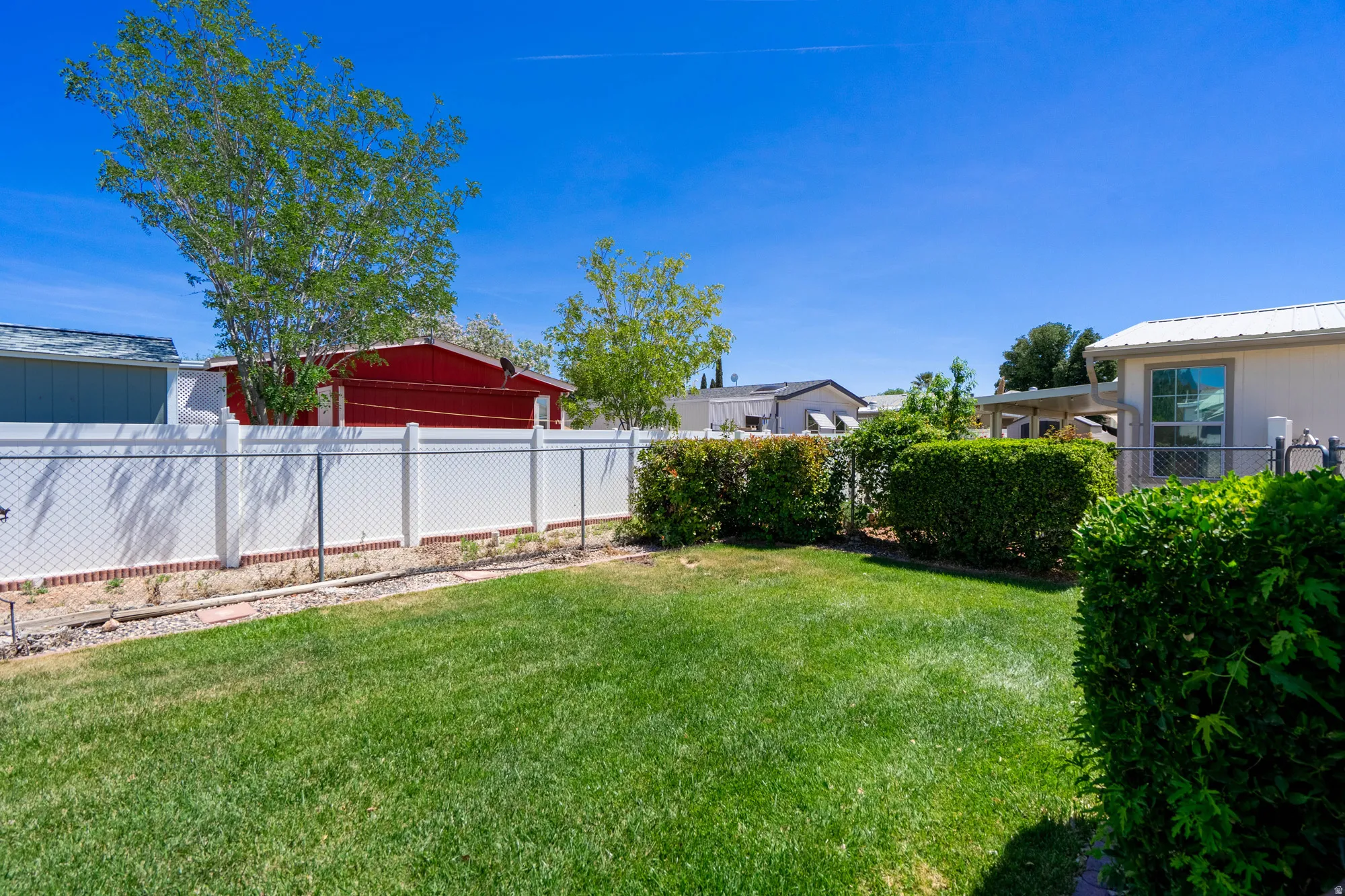 Expansive green lawn with a white vinyl fence perimeter