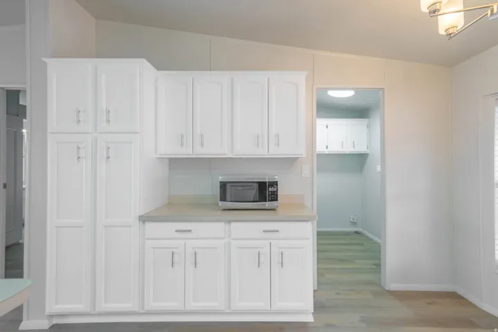 Kitchen featuring white shaker-style cabinetry, a light-toned countertop, and wood-finish flooring