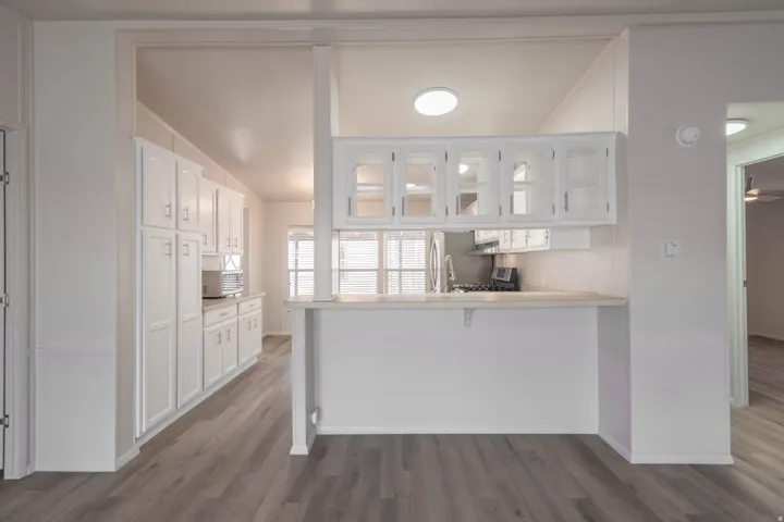 Kitchen area featuring wood-finish flooring, white cabinetry, a built-in breakfast bar, and recessed lighting
