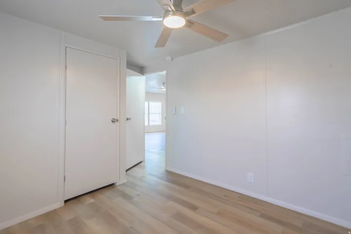Room featuring wood-finish flooring, white walls, and a ceiling fan with integrated lighting
