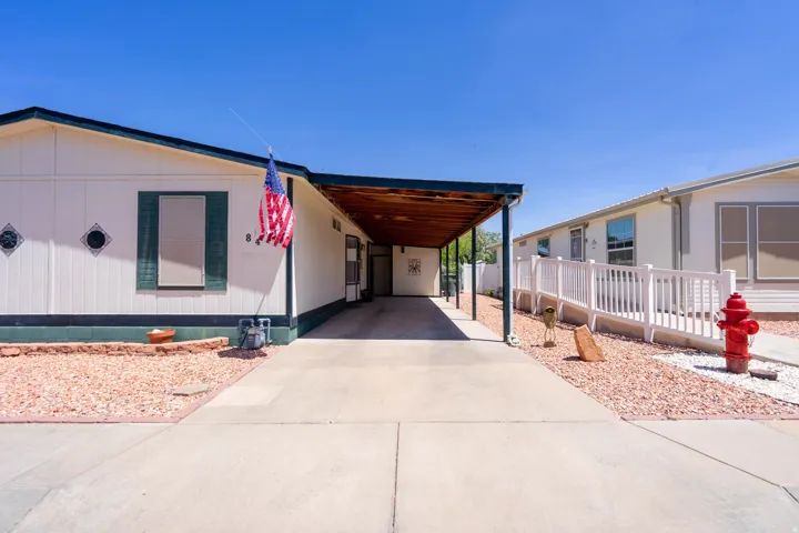 Single-story residence featuring a covered carport, white siding, and green shutters