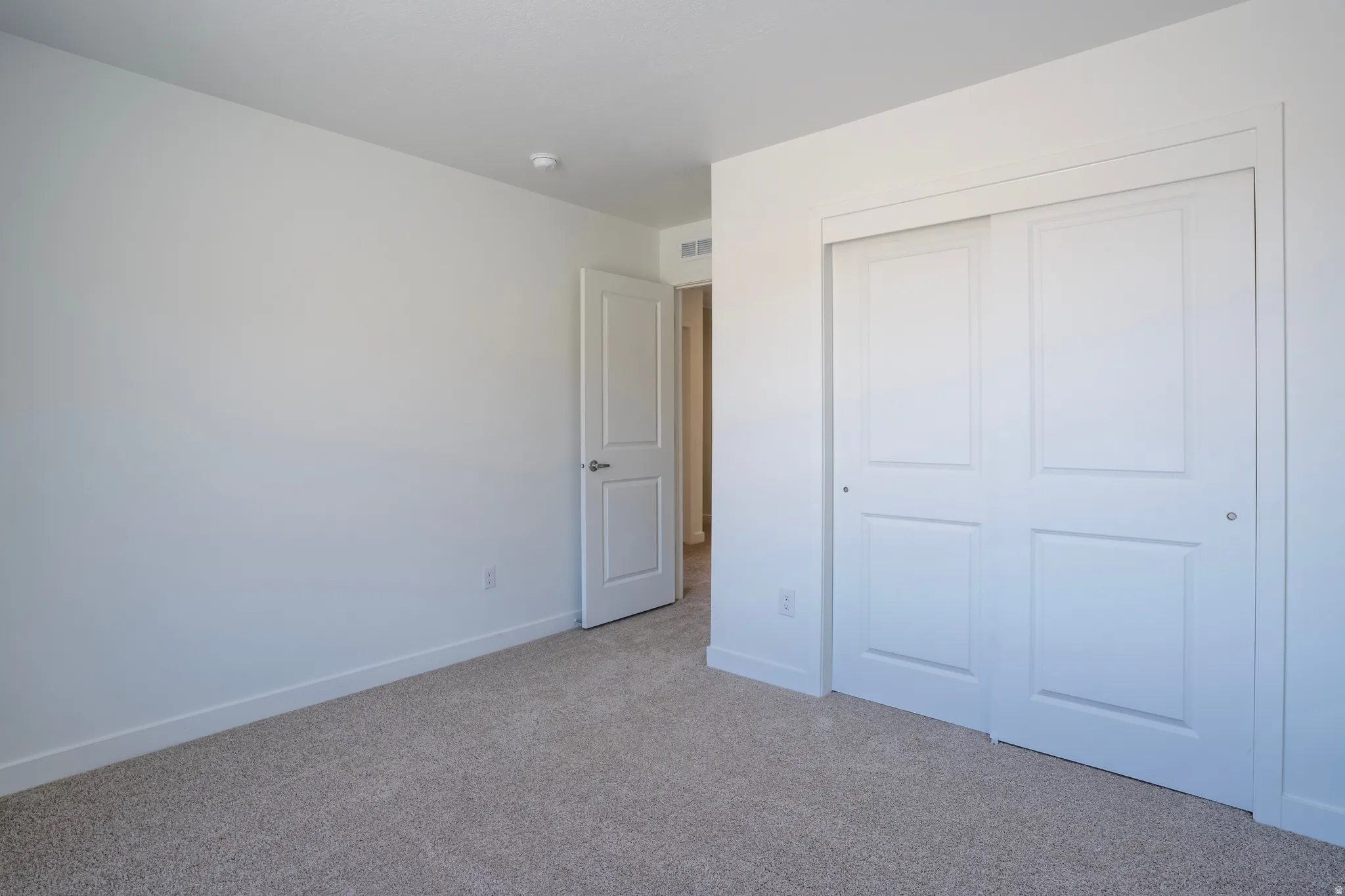Neutral color palette with textured carpeting, white walls, and a recessed light fixture