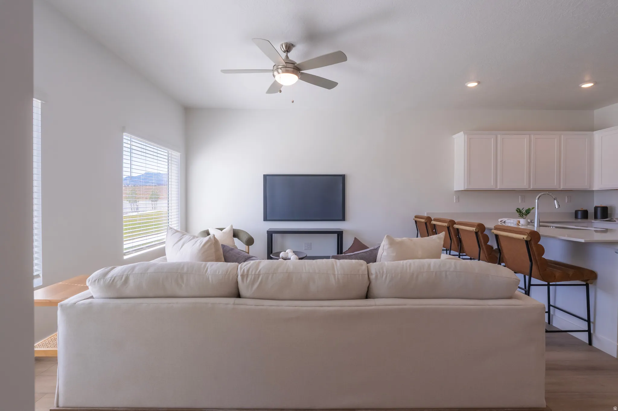 Open concept living space featuring wood-finish flooring, white walls, and a ceiling fan