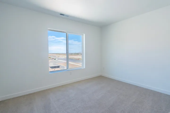 Light-toned carpeting, white painted walls, and a large window with a distant landscape