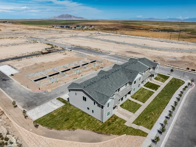 Newly constructed townhouse units featuring light-toned siding, gray shingle roofing, paved walkways, and established green lawns