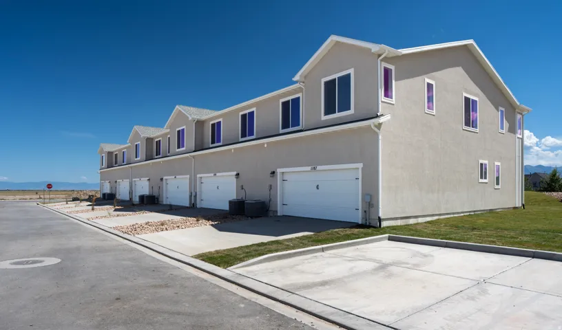 Stucco exterior with multiple dormers, attached garages, and concrete driveways