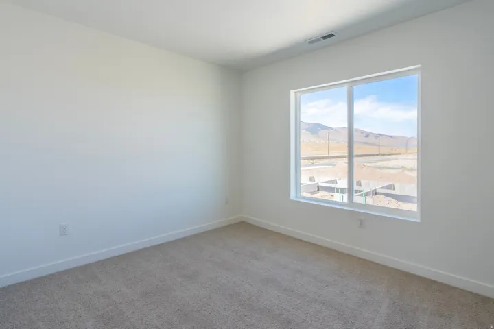 Spacious room featuring neutral carpeting, white walls, and a large window