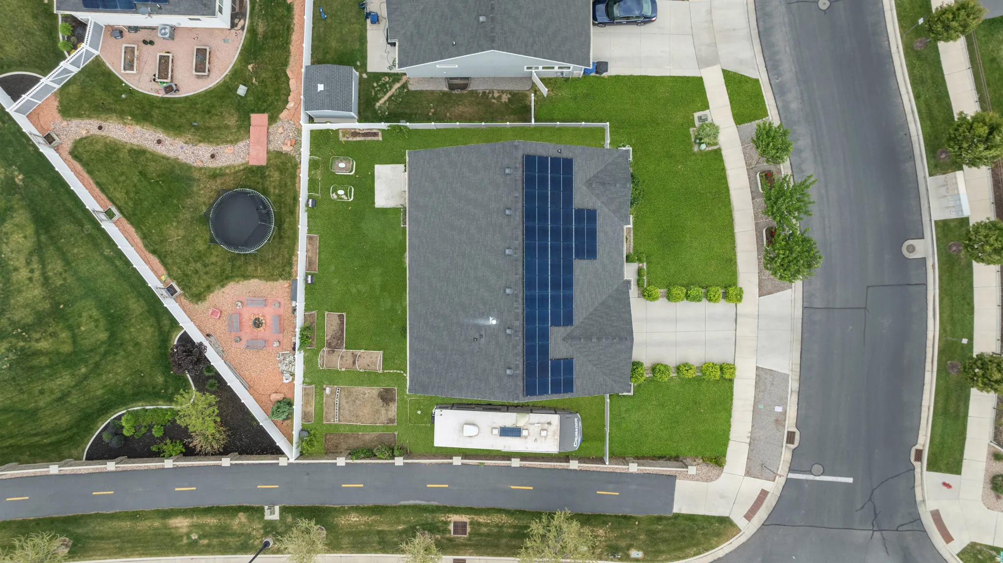 Aerial view showcasing a residential property with a dark shingled roof featuring multiple solar panels