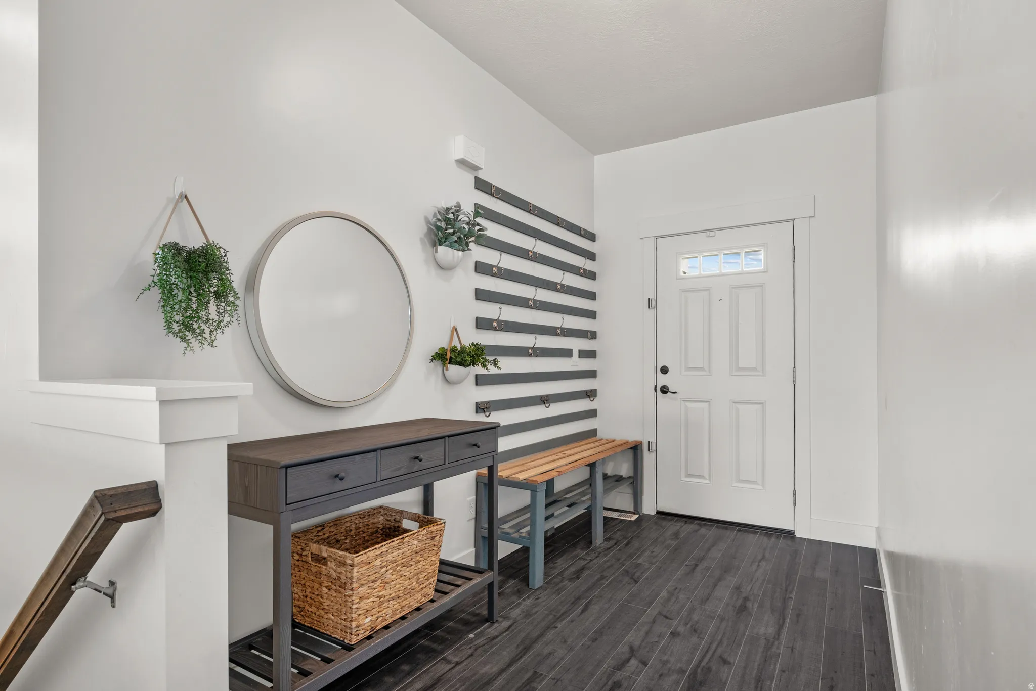 Entryway featuring dark wood-finish flooring, white walls, and a white paneled door with glass inserts. Wall rack and bench included.