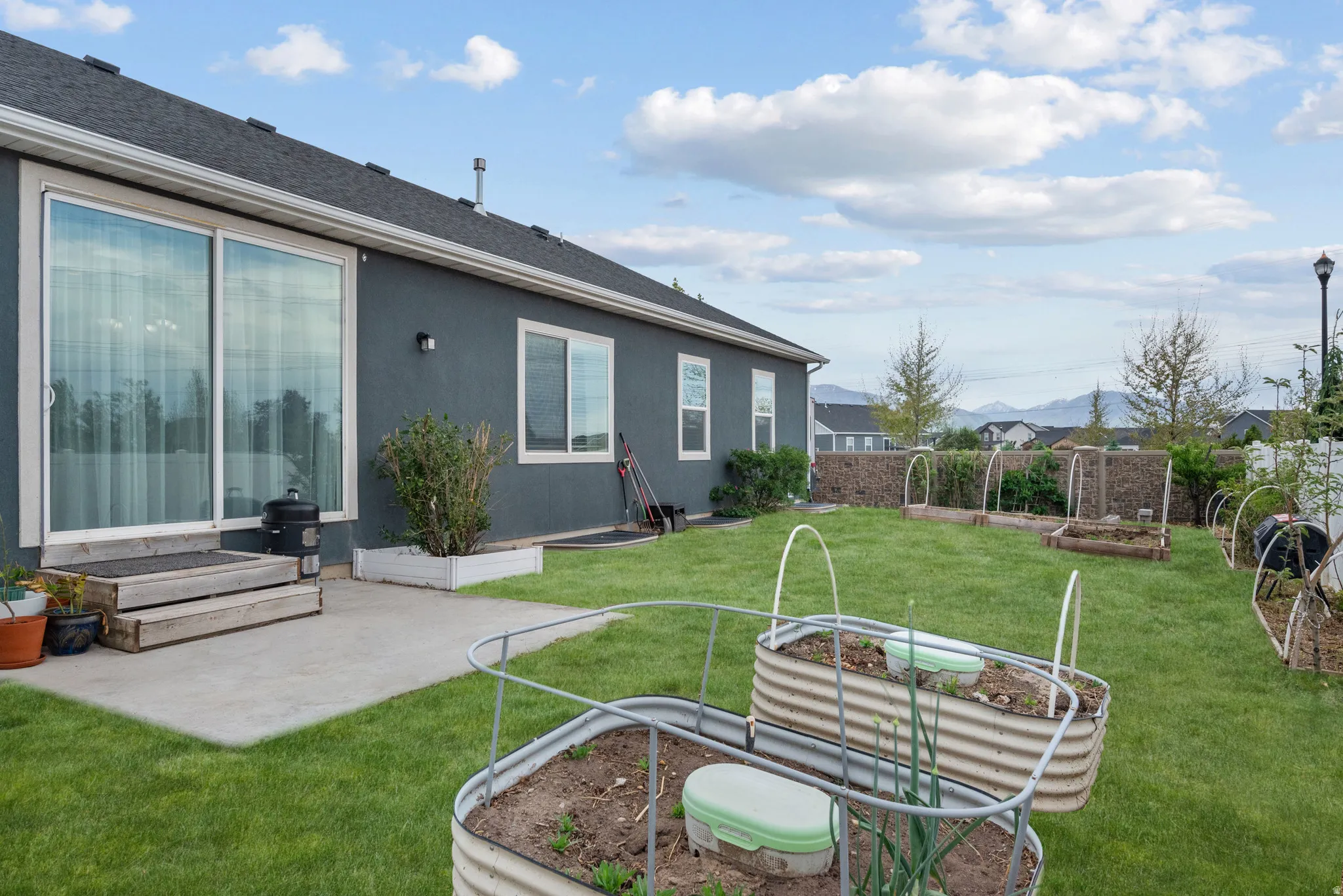 Current backyard with photoshopped green lawn (only the lawn is photoshopped) with established raised garden beds and fruit trees. Fruit trees include nectarin, cherry, apple, raspberries, blackberries, currants and elderberry.