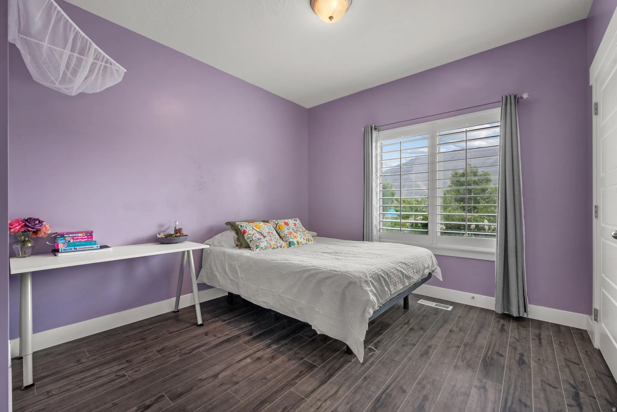 Bedroom . Notice the spectacular view of mountains from the window that has white plantation shutters.