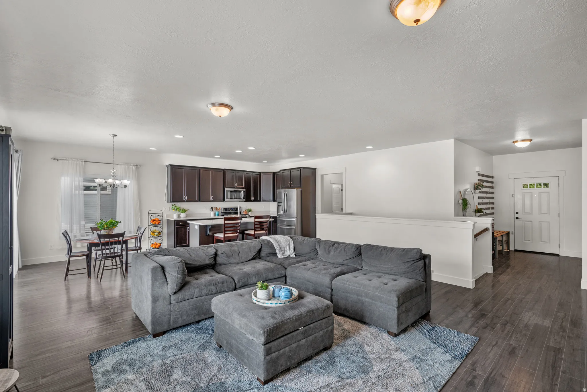 Open concept living space featuring dark wood-finish flooring, white walls, and recessed lighting