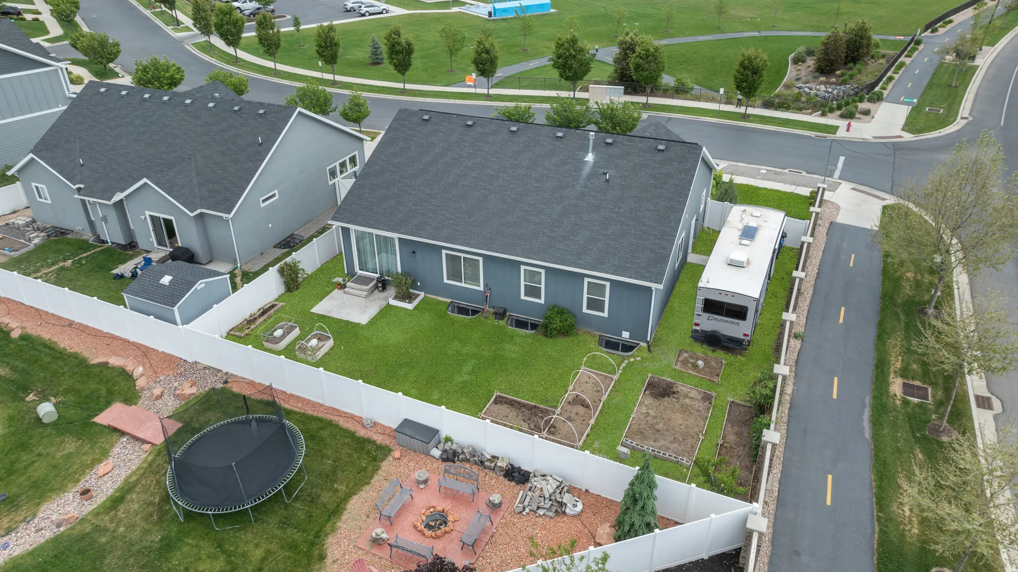 Spacious backyard featuring dedicated garden plots,  a concrete patio, vinyl fencing, RV parking, garden beds, and fruit trees. Notice the park conveniently located across the street.