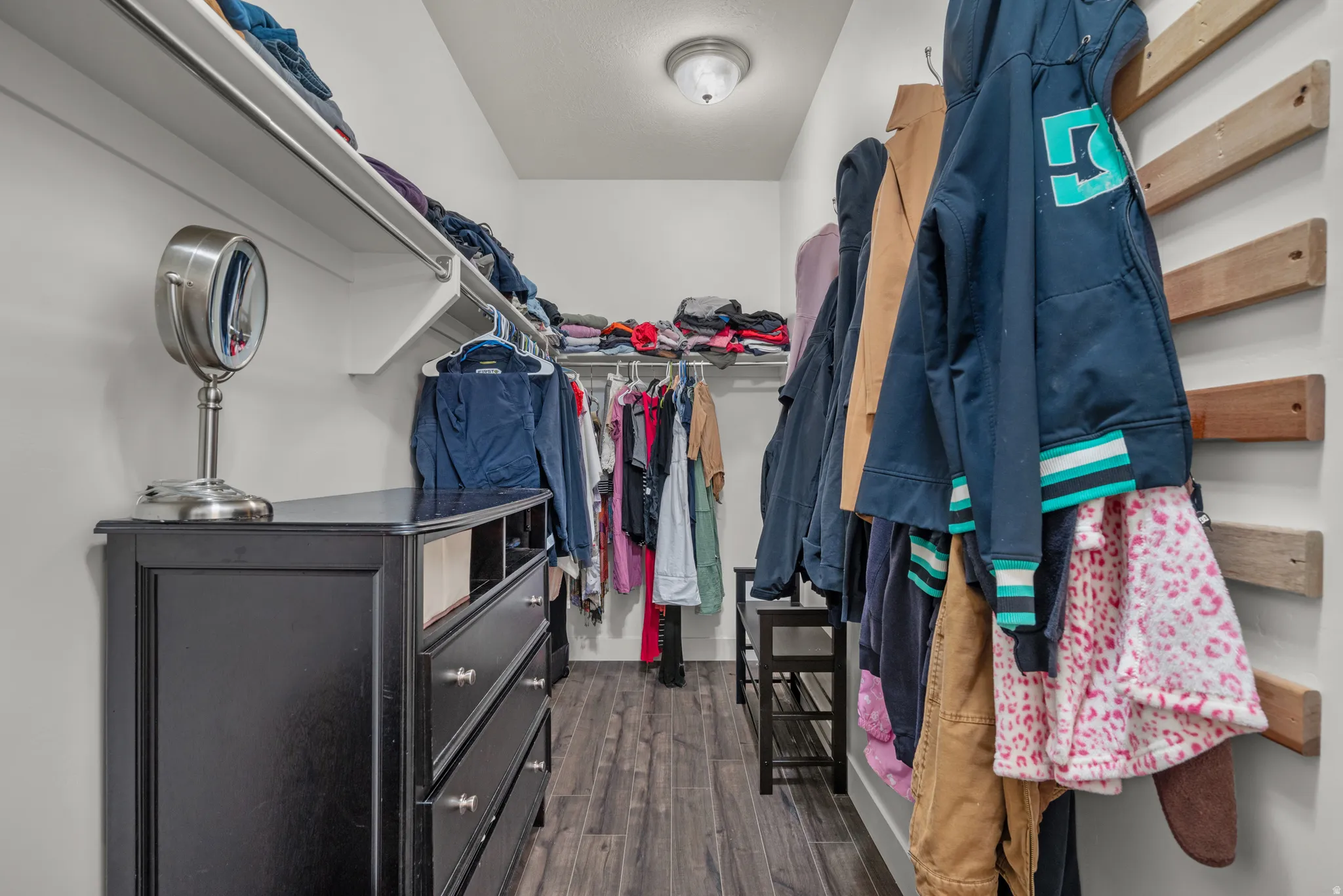 Walk-in closet featuring wood-finish flooring and track shelving