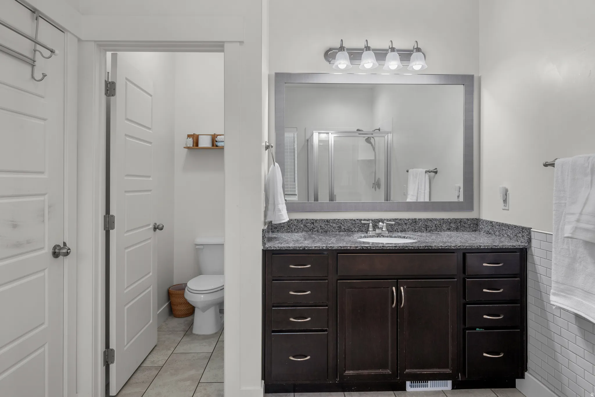 Primary bBthroom vanity featuring a dark wood-finish cabinet, granite countertop  and an undermount sink.