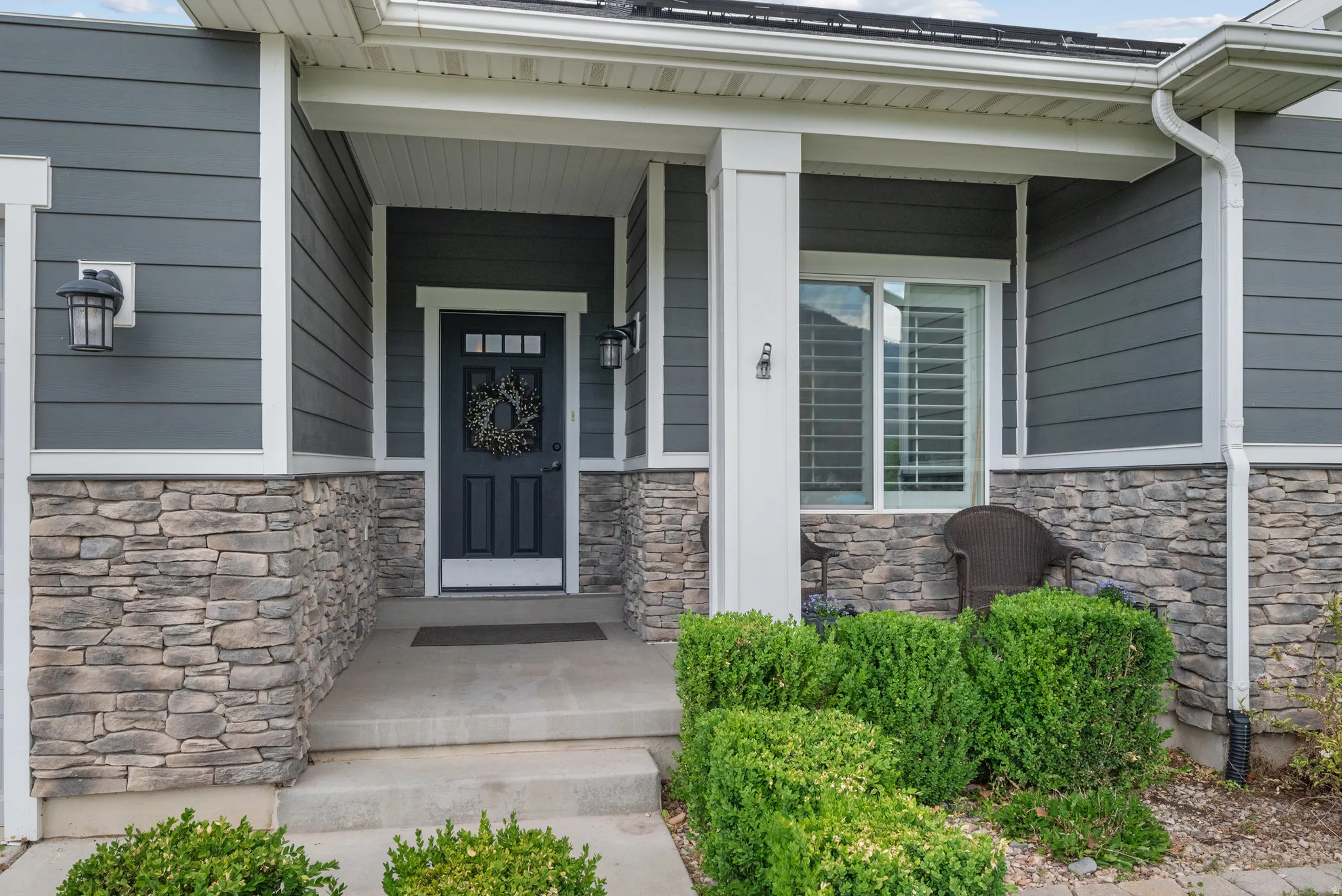 Exterior featuring stone accents, horizontal siding, covered entry, and a dark paneled door with glass inserts. Enjoy spectacular mountain views and views of Legacy Farm park from the front porch.