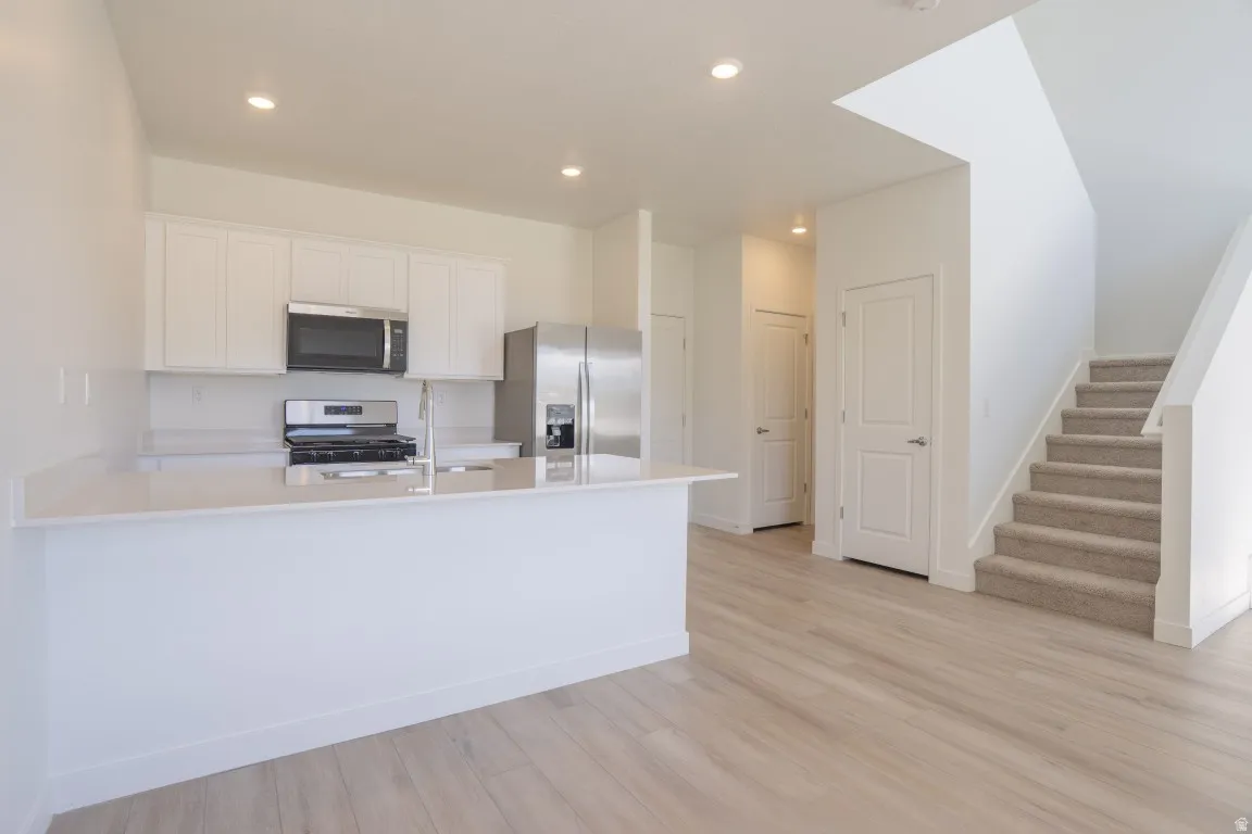 Kitchen featuring white cabinetry, stainless steel appliances, and light-toned countertops