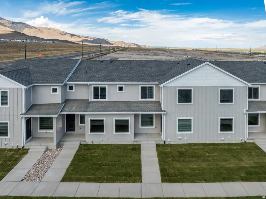 Contemporary townhome exterior with light gray siding, dark gray shingle roof, and white trim windows